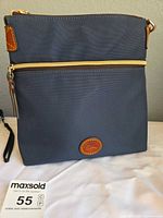 Front view showing navy nylon body, exterior zip pocket, leather logo patch, gold-tone zipper