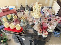 All items laid out on table including lantern, sleigh, candles, mosaic bells, Santa figurine, glass candle holders and jar ornaments