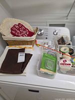 Overall lot on washer: basket, linens, oven mitt, organizer box with supplies