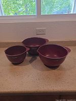 Three nested burgundy KitchenAid bowls on countertop