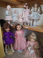 Group of eight collectible dolls on shelf