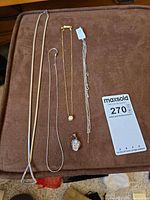 All five jewellery pieces laid out: four necklaces and one pendant