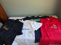 Four T-shirts laid out showing colours and graphics