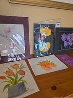 All five floral paintings displayed, some standing, some laid flat