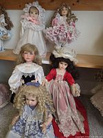 Group of five Victorian-style porcelain dolls on shelves