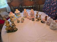 Overview of entire lot on table showing all resin houses, figurines, eggs, glass votives