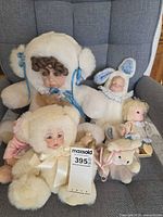 Group shot of all porcelain face dolls and plush toys on chair