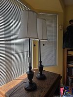 Both matching bronze table lamps with white shades on table