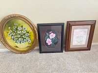 All three framed artworks standing against wall