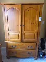Front view of closed armoire showing doors, drawers, hardware and finish