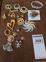 Entire assortment of brooches, earrings, bracelet and pins laid out on brown cloth