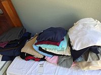 Two folded stacks of assorted women’s tops and sweaters