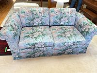 Front view of 2-seater floral sofa showing rolled arms and skirt