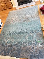 Full view of the 6' x 9' abstract blue/teal/gray area rug on hardwood floor