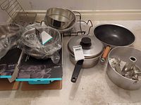 Full lot showing boxed Vivo items, steamer baskets, saucepan with lid, wok, bundt pan with cookie cutters and wire rack