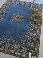 Full view of blue wool rug showing central medallion and border