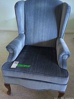 Front view of blue corduroy wingback armchair showing seat cushion and wooden legs