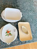 Group shot showing square casserole, round platter, oval floral dish, beige rectangular baker, beige sauce boat