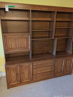 Front view showing entire wall unit with shelves, drop-front, drawers, cabinets