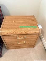 Front view of light oak two-drawer nightstand showing brass-tone handles