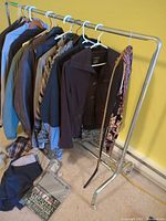 Full view of garment rack with hanging clothes, belts, ties and folded items on floor