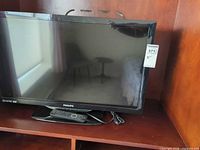 Front view of Philips 32-inch TV on shelf with remote and power cable