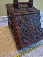 Front view showing carved scroll design and measuring tape