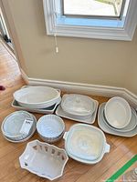 Group shot of all white ceramic dishes, glass lids visible
