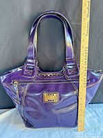 Full view of purple patent leather tote with ruler for scale