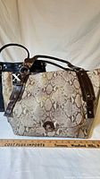 Front view showing both handbags, snake print tote in foreground, black quilted bag behind