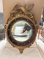 Front view of convex mirror with eagle crest and gilt frame