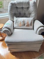 Front view of upholstered swivel armchair with pillow