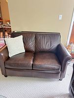 Front view showing leather loveseat, seat and back cushions, accent pillow
