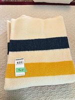 Folded blanket with navy and yellow stripes, size tag visible