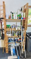 Full view of shelving with long-handled tools and assorted chemicals