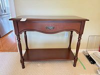 Front view of console table showing overall design, drawer, lower shelf and legs