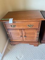 Front view of maple nightstand showing drawer, cabinet doors, brass hardware