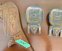 Front view of carved yellow cedar raven plaque and two stands with 13.5 in tape for scale