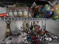 Shelves showing glass egg ornaments, plush dinosaur, metallic rabbits and other figures