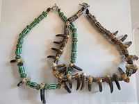 Overall view of two bear claw necklaces showing bead materials and clasps