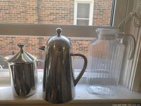 Three items: Palm stainless carafe, stainless French press, clear glass pitcher