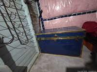 Closed trunk showing blue painted metal exterior with brass trim and latch