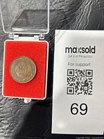 Coin in open display capsule next to lot card