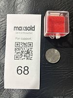 Coin, display box and paper tag on black surface