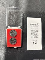 Front view of both coins in open plastic display case, reverse sides visible