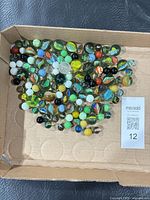 Full group of assorted multicolor marbles in box lid