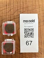 Overview of both coins inside clear plastic holders next to lot tag