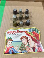 Needle book cover with nine thimbles arranged in front