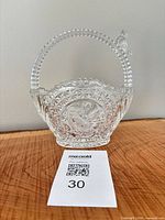 Front view of clear pressed glass basket showing bird medallion and handle with bird finial