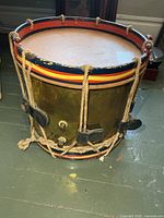 Oblique view of brass rope-tension drum showing shell, hoops, rope and leather ears